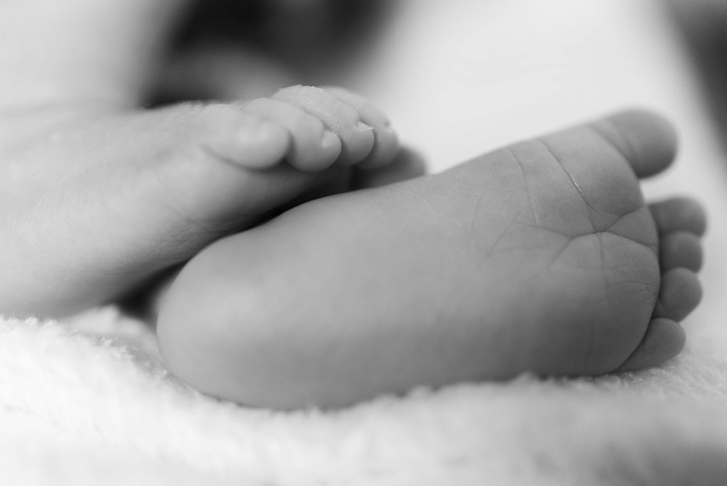 Adorable close-up of newborn baby feet in grayscale, emphasizing the tiny toes and delicate skin.