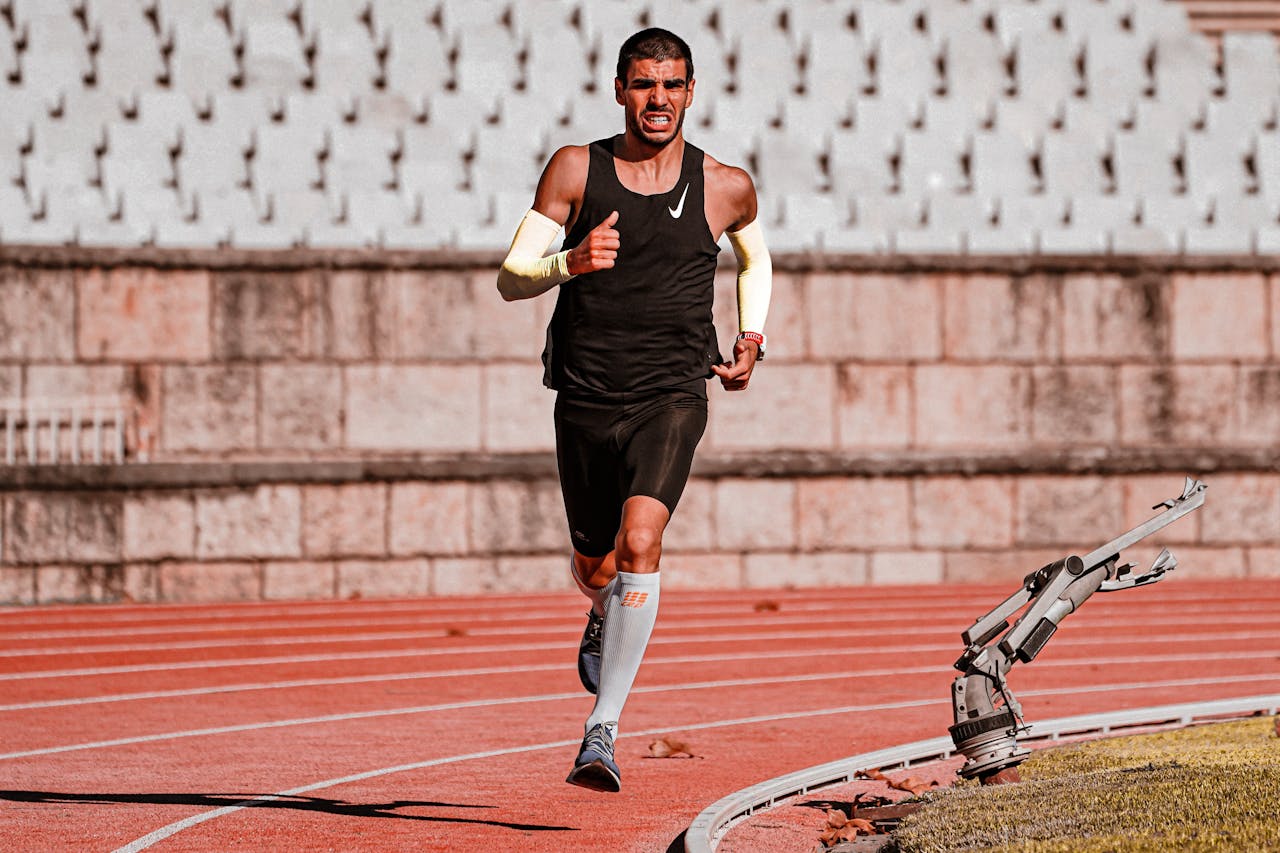 Podologie du sport : comment protéger vos pieds si vous courez Focused male runner during a track race, showcasing determination and endurance.